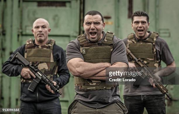 krav maga fighting group posing for team picture with weapons in grimy outdoor setting - committee of public security and fight stock pictures, royalty-free photos & images