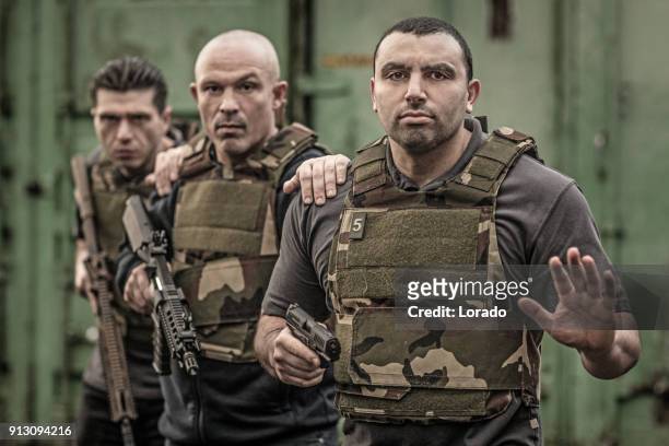 krav maga fighting group posing for team picture with weapons in grimy outdoor setting - committee of public security and fight stock pictures, royalty-free photos & images