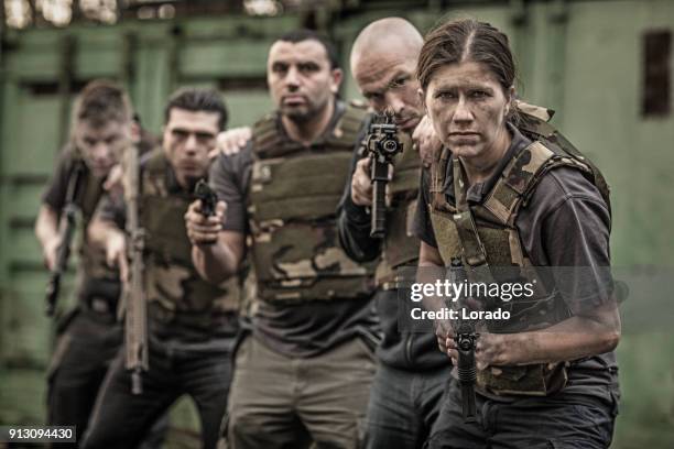 krav maga fighting group posing for team picture with weapons in grimy outdoor setting - committee of public security and fight stock pictures, royalty-free photos & images