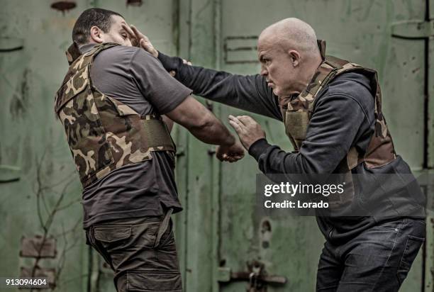 krav maga fighting duo sparring during training session in grimy outdoor setting - krav maga stock pictures, royalty-free photos & images