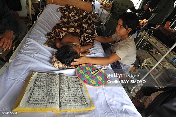 Members of a family put a Koran next to the head of their child in a makeshift ward of M. Djamil general hospital in the Sumatran city of Padang...