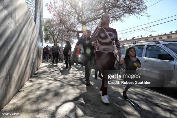 Parents and family members rush along Crown Hill Avenue toward a meeting point outside the Belmont High School complex in hopes of reuniting with...