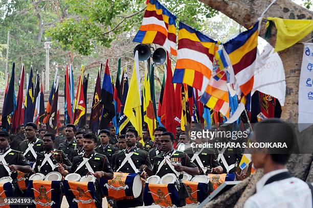 Sri Lankan soldiers hold aloft regimental flags as they take part in a Buddhist ceremony where the military offered flags belonging to army regiments...