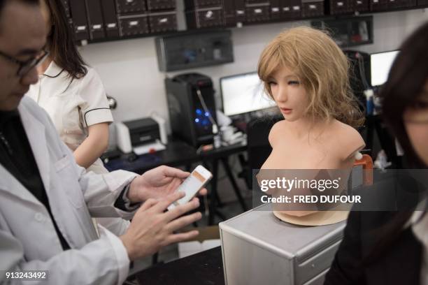 This photo taken on February 1, 2018 shows an engineer displaying the facial expressions a robot can make, in a lab of a doll factory of EXDOLL, a...