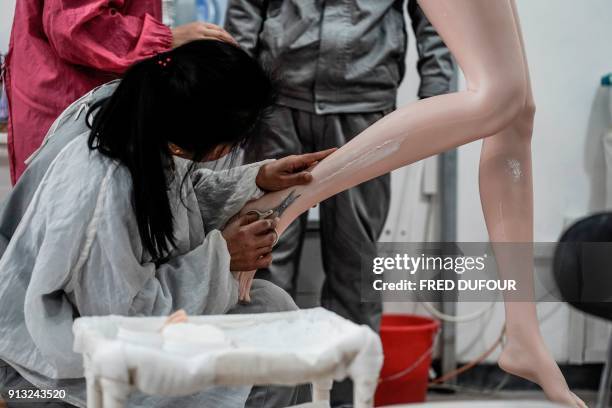 This photo taken on February 1, 2018 shows a worker trimming the skin imperfections of a silicone doll at a factory of EXDOLL, a firm based in the...