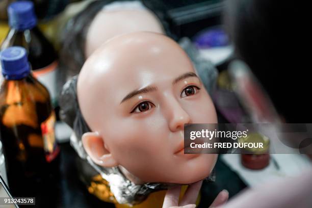 This photo taken on February 1, 2018 shows a worker painting the face of a silicone doll at a factory of EXDOLL, a firm based in the northeastern...