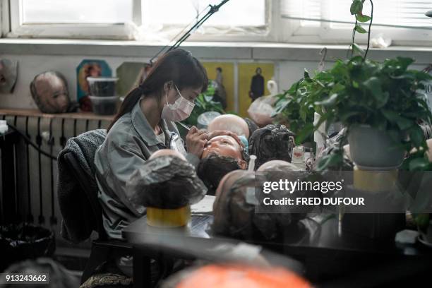 This photo taken on February 1, 2018 shows a worker painting the face of a silicone doll at a factory of EXDOLL, a firm based in the northeastern...