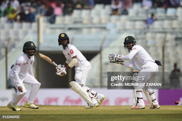 Sri Lanka cricketer Kusal Mendis plays a shot as the Bangladesh cricketer Mominul Haque and Liton Das look on during the third day of the first...