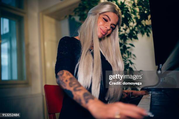 beautiful young woman playing piano indoors - performing arts occupation stock pictures, royalty-free photos & images