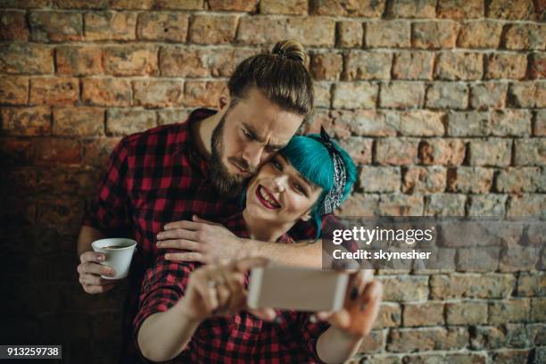 young embraced couple having fun while taking a selfie with smart phone. - pin up wall stock pictures, royalty-free photos & images