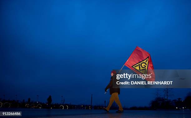 Member of the metalworkers' and electrical industry union holds an Ig Metall flag near a ferry dock in Teufelbrueck, northern Germany on February 02,...