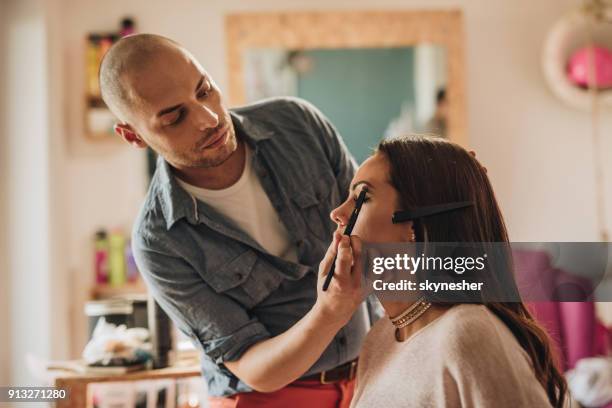 männlichen make-up artist lidschatten auf junge frau augen anwenden. - beautician stock-fotos und bilder