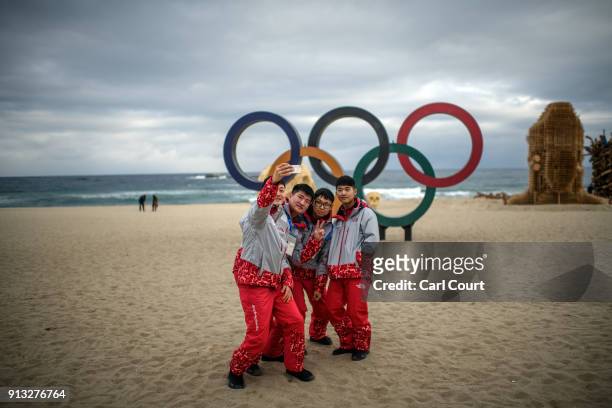 Group of Olympics volunteers take a selfie photograph next to Olympic rings on the beach near the Gangneung Coastal Cluster on February 2, 2018 in...
