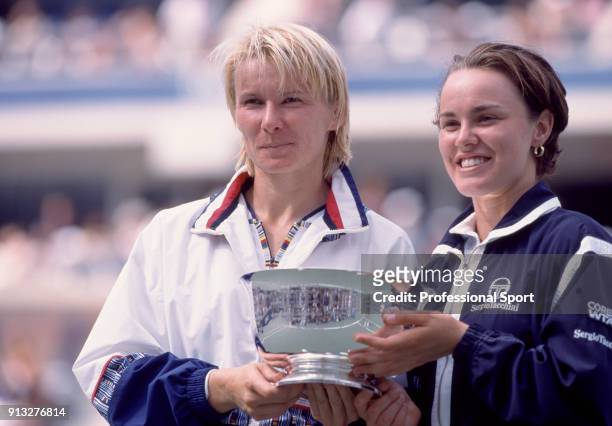 Doubles partners Martina Hingis of Switzerland and Jana Novotna of the Czech Republic pose with the trophy after defeating Lindsay Davenport of the...