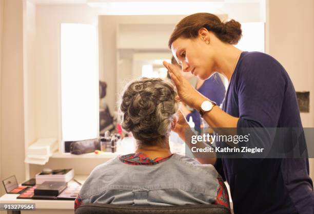 senior woman having her hair and makeup done by makeup artist before stage performance - backstage mirror stock pictures, royalty-free photos & images