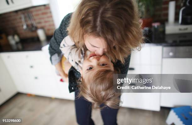 a mum having fun with her 1 year old baby boy in the kitchen - blond boy stock-fotos und bilder