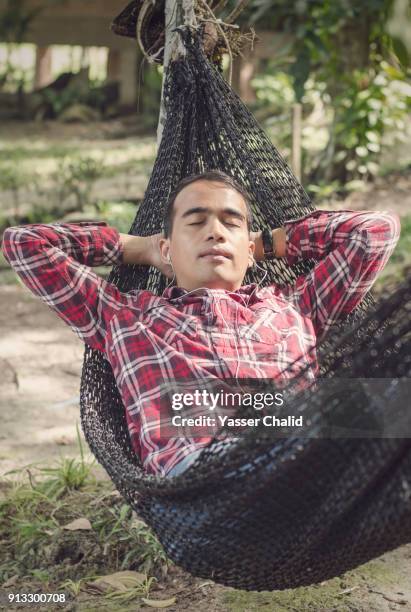 indonesian man sleeping on hammock - young man listening music and relaxing in hammock stock pictures, royalty-free photos & images