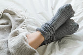 Feet crossed with gray socks on bed under blanket