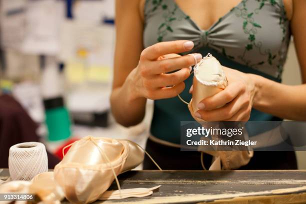 dancer at pointe shoe department preparing her shoes, close-up of hands - calzature sportive foto e immagini stock