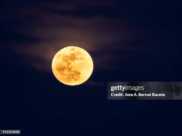 full frame of the supermoon of yellow color on a black sky with some high clouds. valencia, spain - full moon 個照片及圖片檔