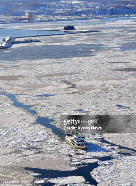 Photo taken from a Kyodo News airplane shows an icebreaker carrying tourists sails through drift ice in the Sea of Okhotsk off Abashiri on Japan's...