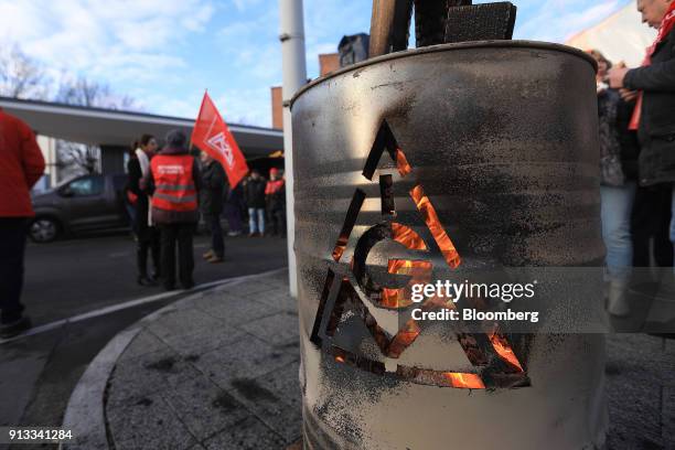 The IG Metall logo sits on a burning brazier barrel during a 24 hour strike called by the labor union outside the BMW Motorrad motorcycle factory,...
