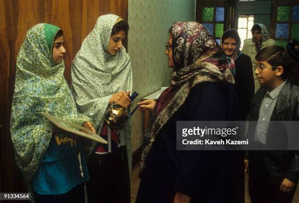 Two girls holding a mirror and a jug of rose water as they greet guests at the entrance to the Zoroastrian association hall in Tehran, Iran, 22nd...