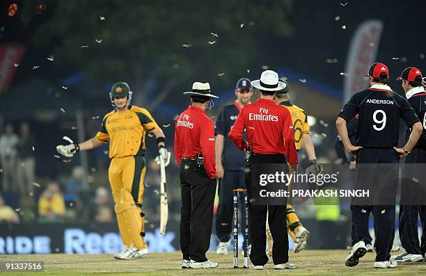 Umpires and cricketers wait for game to resume as hundreds of insects fly over the ground during the ICC Champions Trophy's first semi final match...