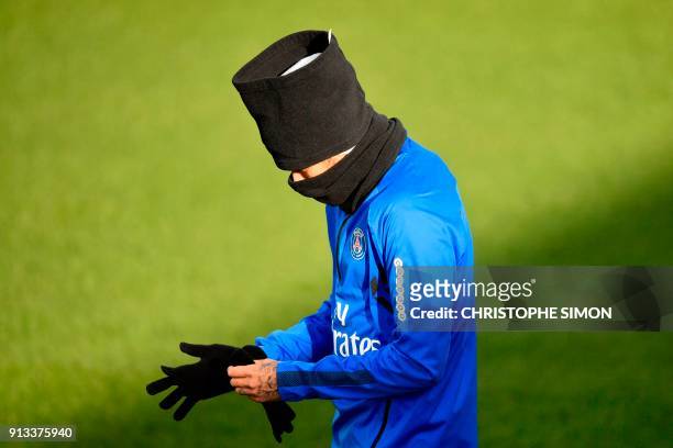 Paris Saint-Germain's Brazilian forward Neymar puts on gloves as he arrives to take part in a training session of the Paris Saint-Germain football...