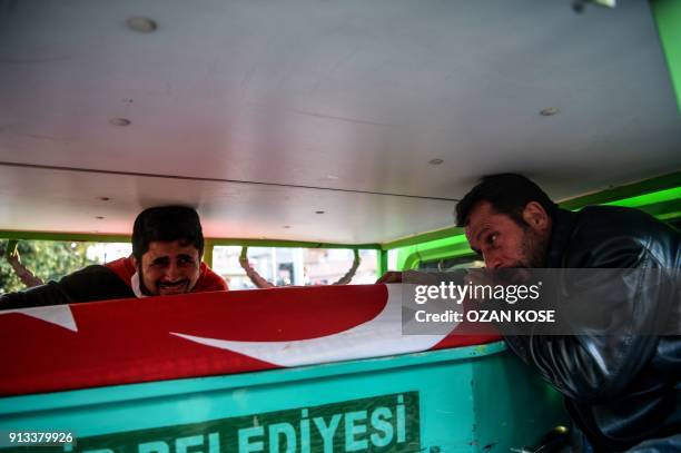 People react over a coffin covered with a Turkish flag during a funeral cerenomy for a man killed by rocket fire in Reyhanli, a town close to the...