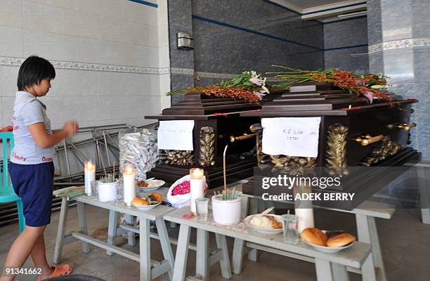 Girl pays her respects before the caskets of victims of the recent earthquakes in Padang on October 2, 2009. Indonesia said it feared thousands had...