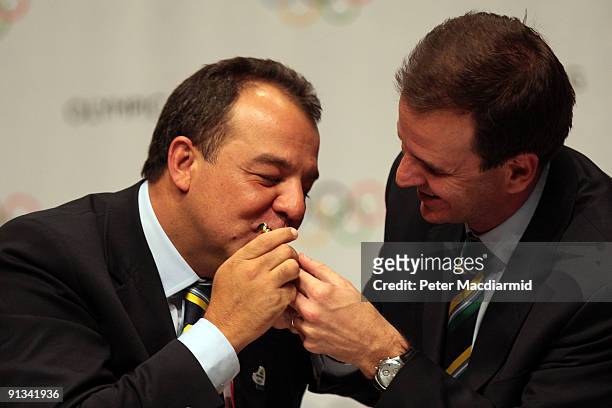 The Governor of Rio Sergio Cabral kisses the pen to sign the Host City contract next to the Mayor of Rio Eduardo Paes during a press conference after...