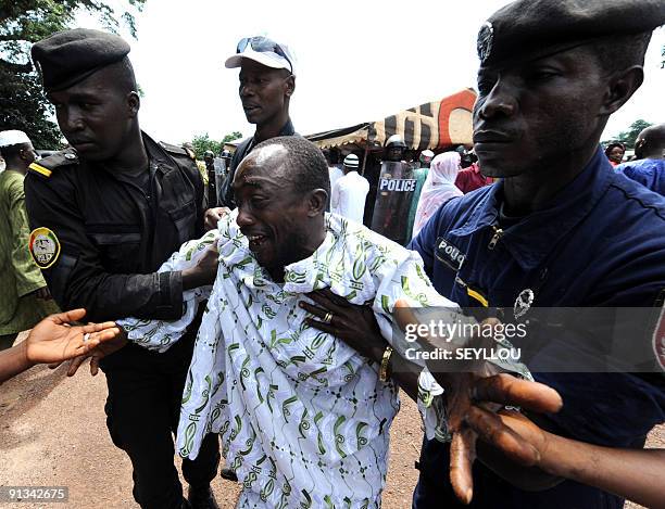 Police help on October 2, 2009 a man grieving as he arrives in front of the Conakry great mosque, where several dozen bodies of victims shot dead by...