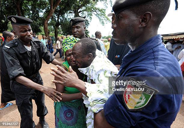 Police help on October 2, 2009 a man grieving as he arrives in front of the Conakry great mosque, where several dozen bodies of victims shot dead by...