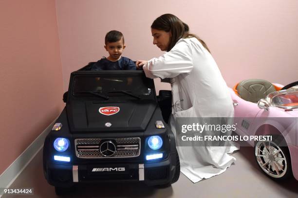 Medical staff speaks with two-year-old Souhail sitting in an electric toy car before going to the operating room at the Valenciennes Hospital in...