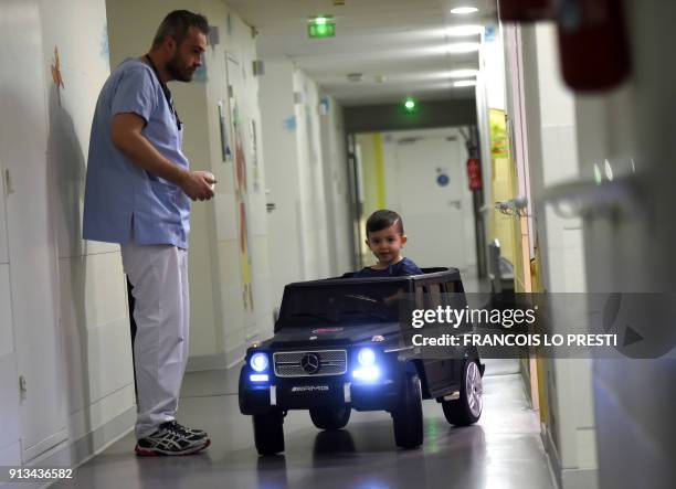 Two-year-old Souhail sits in an electric toy car on his way to the operating room at the Valenciennes Hospital in Valenciennes, northern France, on...