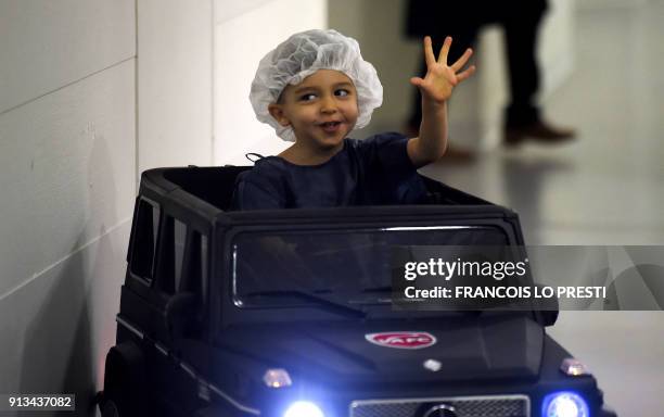 Two-year-old Souhail waves to medical personnel as he sits in an electric toy car on his way to the operating room at the Valenciennes Hospital in...