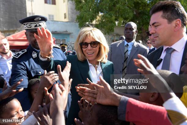Wife of French President Brigitte Macron shakes hands with children during a visit to the medina district of Dakar on February 2, 2018. / AFP PHOTO /...