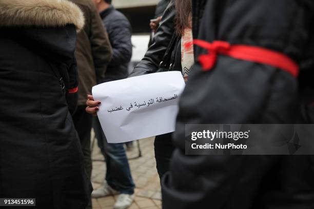 Tunisian journalists wear red ribbons around their arms during a demonstration held under the slogan Tunisian press in anger, outside the headquarter...