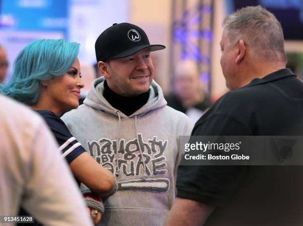 Boston actor Donnie Wahlberg, center, and his wife, actress Jenny McCarthy. Left, chat with former New England Patriots offensive coordinator Charlie...