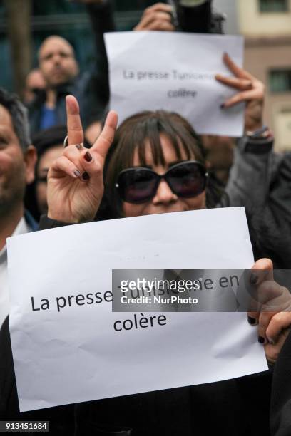 Female Tunisian journalist makes a victory sign as she holds a placard which reads 'Tunisian press in ange, during a demonstration held under the...