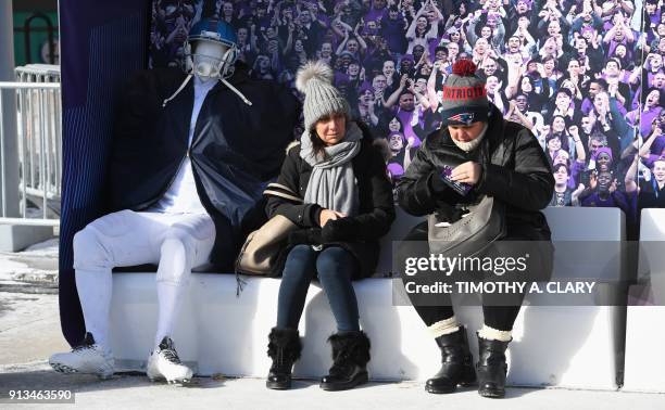 People sit on a warming bench in cold weather during the Super Bowl LIVE, a 10-day fan festival leading up to Super Bowl LII, taking place on...