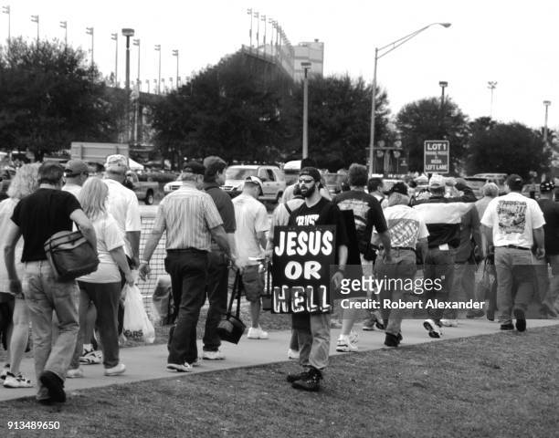 Man wearing a 'Jesus or Hell' sign hands out religious literature to race fans outside the speedway prior to the start of the 2003 Daytona 500 stock...
