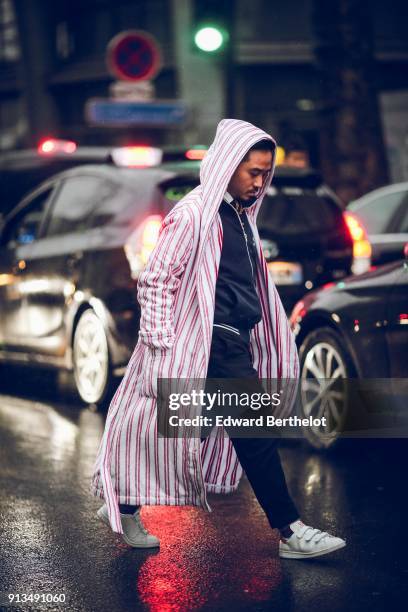 Guest wears a red and white striped coat with a hood, under the rain, outside Paul Smith, during Paris Fashion Week - Menswear Fall Winter 2018-2019,...