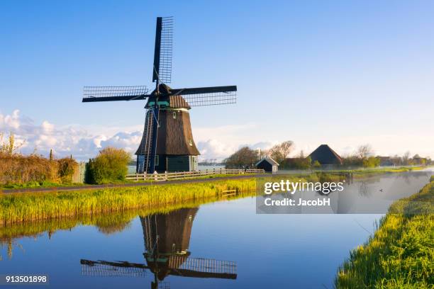 windmill along a canal - netherlands windmill stock pictures, royalty-free photos & images