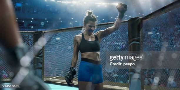 professional female mixed martial arts fighter raising fist in victory - combat sport stock pictures, royalty-free photos & images