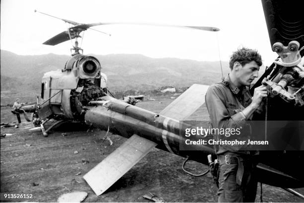 An unidentified US Army pilot salvages part of the tail rotor from his destroyed Bell UH-1 Iroquois helicopter, better known as a Huey , Khe Sanh,...