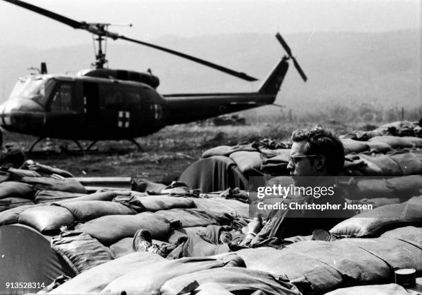 View of an unidentified US Army medevac crew member as he sits among sandbags between flights, Khe Sanh, Republic of Vietnam, February 25, 1971. He...