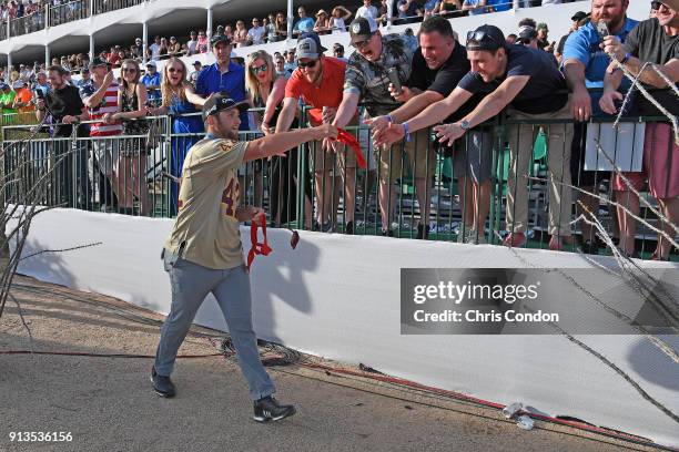 Jon Rahm of Spain gives gifts to fans at the 16th hole during the second round of the Waste Management Phoenix Open at TPC Scottsdale on February 2,...