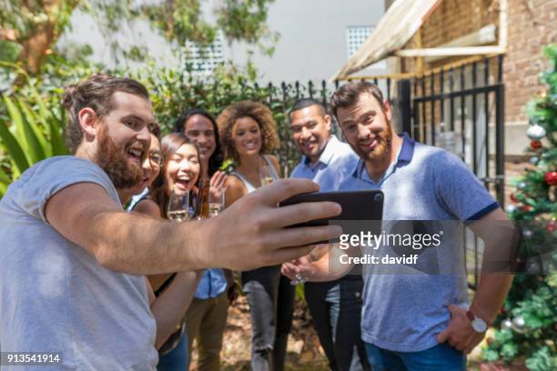 group of mixed race people taking a selfie at a christmas party - sydney christmas lights 2017 stock pictures, royalty-free photos & images